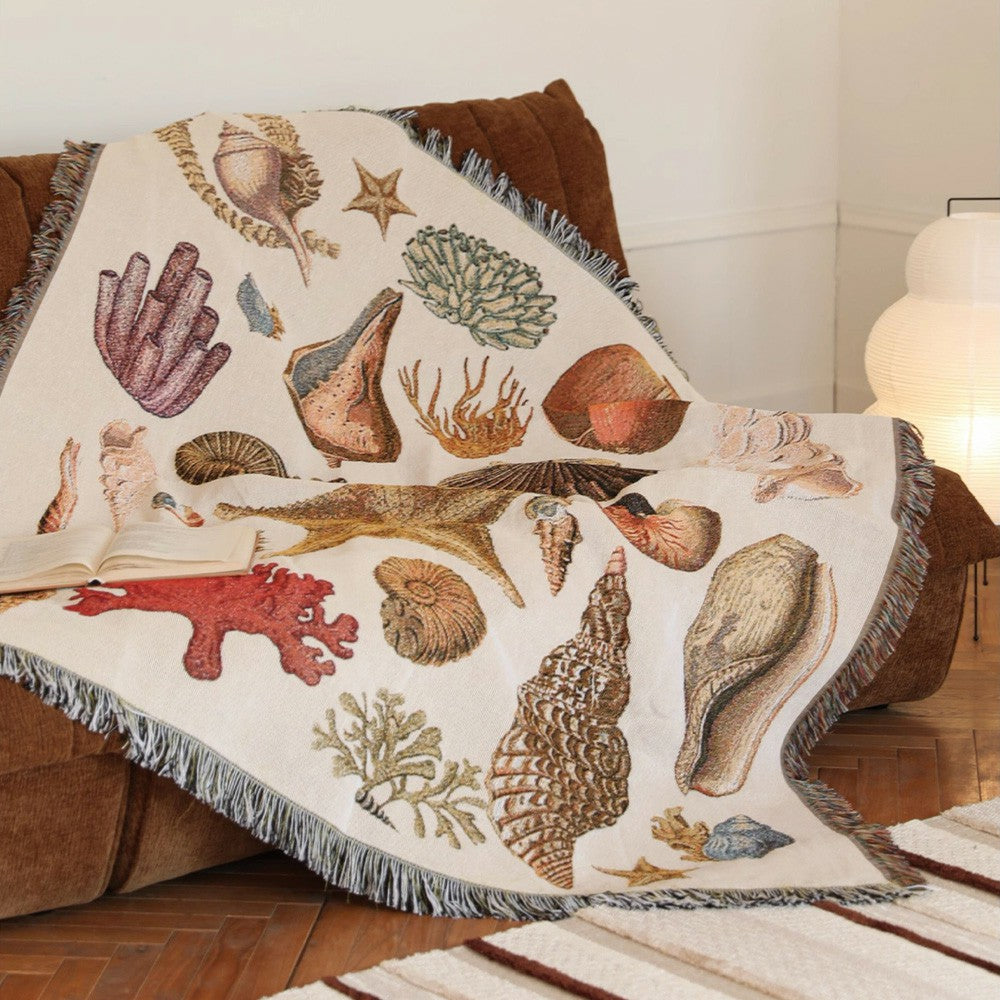 Coastal woven throw blanket styled over a brown armchair in a reading corner.
