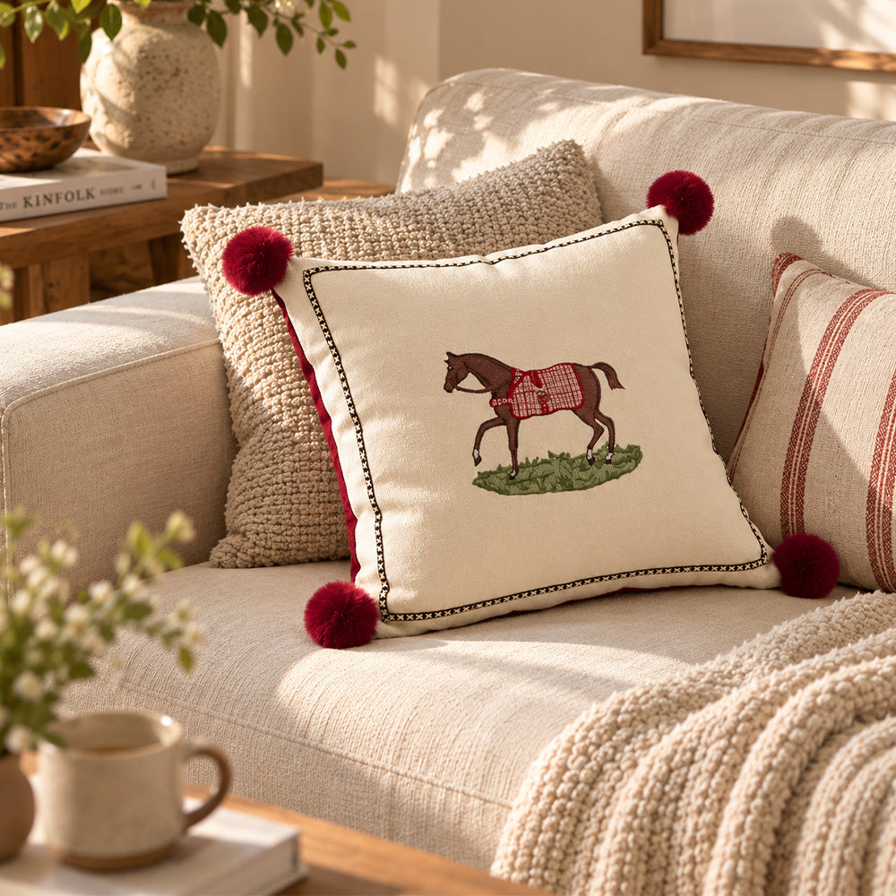 Cream horse pom pom pillow cover styled with neutral textured cushions on a sofa
