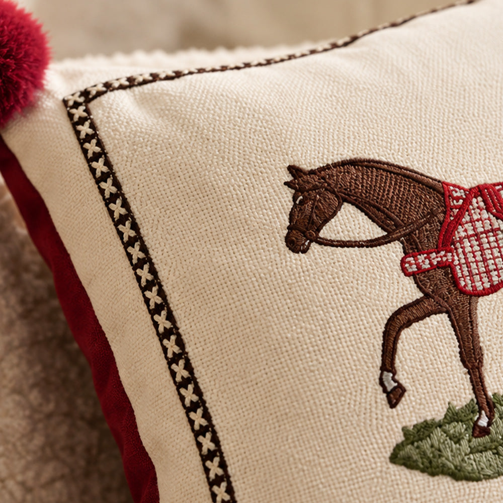Close-up of embroidered brown horse, red blanket, contrast border and cream fabric texture