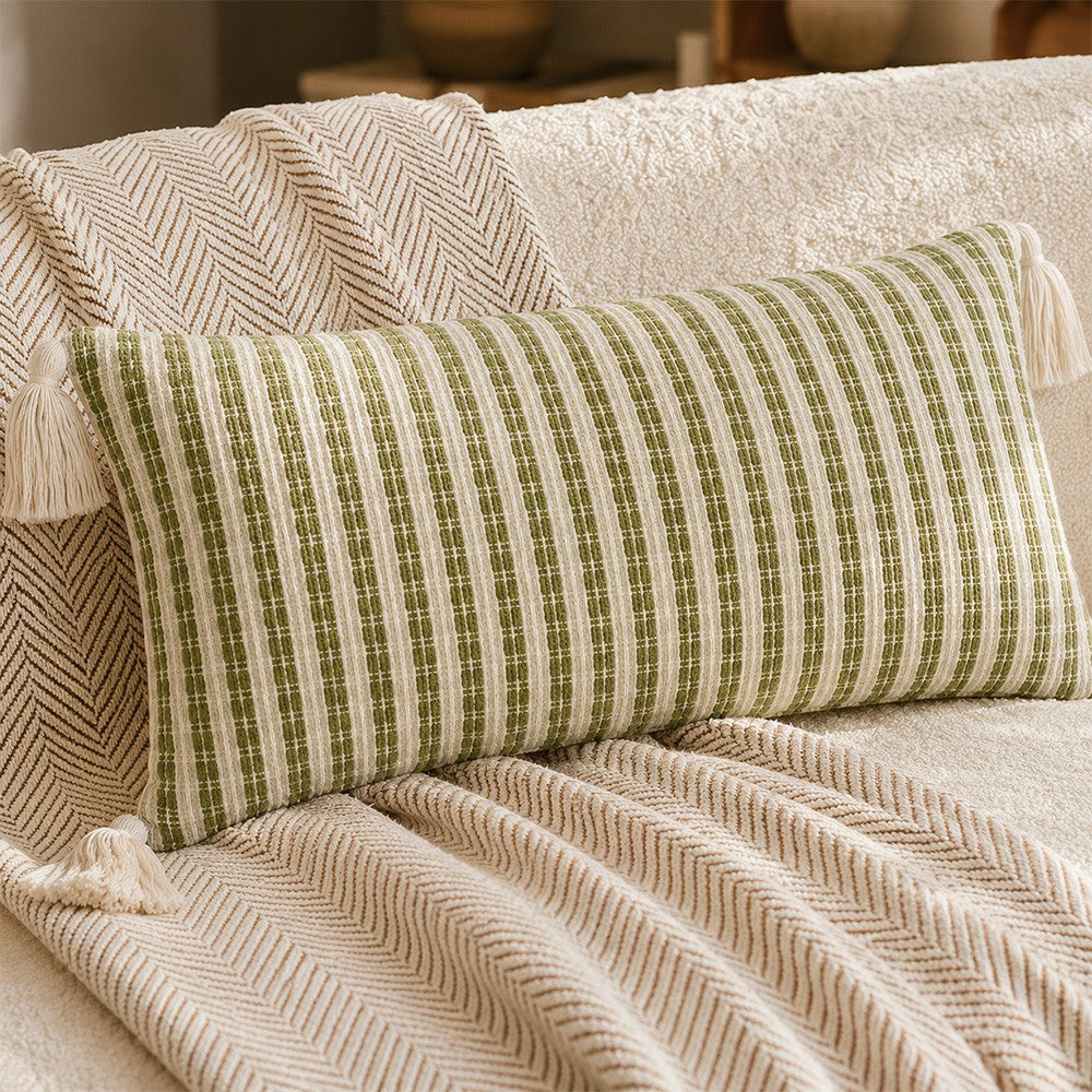 Angled close-up of green and cream textured lumbar pillow cover with tassels on a sofa