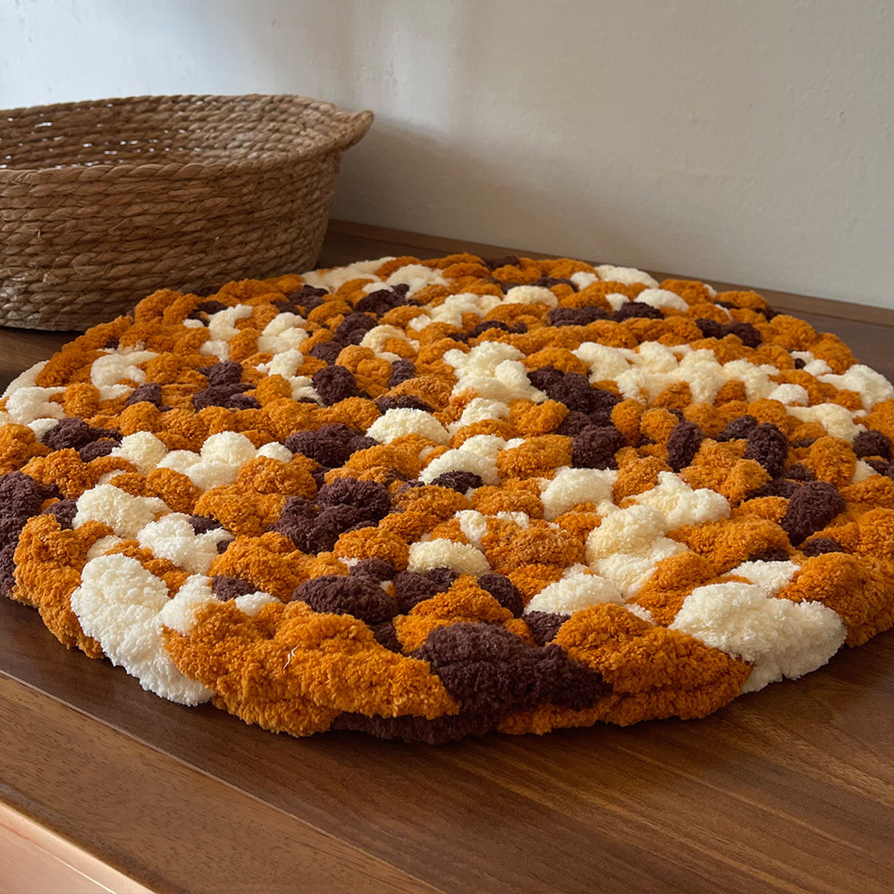 Pebble mustard-brown chenille round seat cushion on a wood surface
