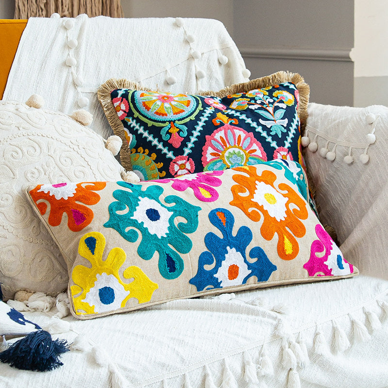 Colorful embroidered boho throw pillows styled together on a cozy white sofa.
