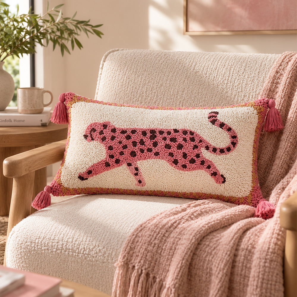 Pink tufted leopard tassel lumbar pillow cover displayed on a cream boucle armchair