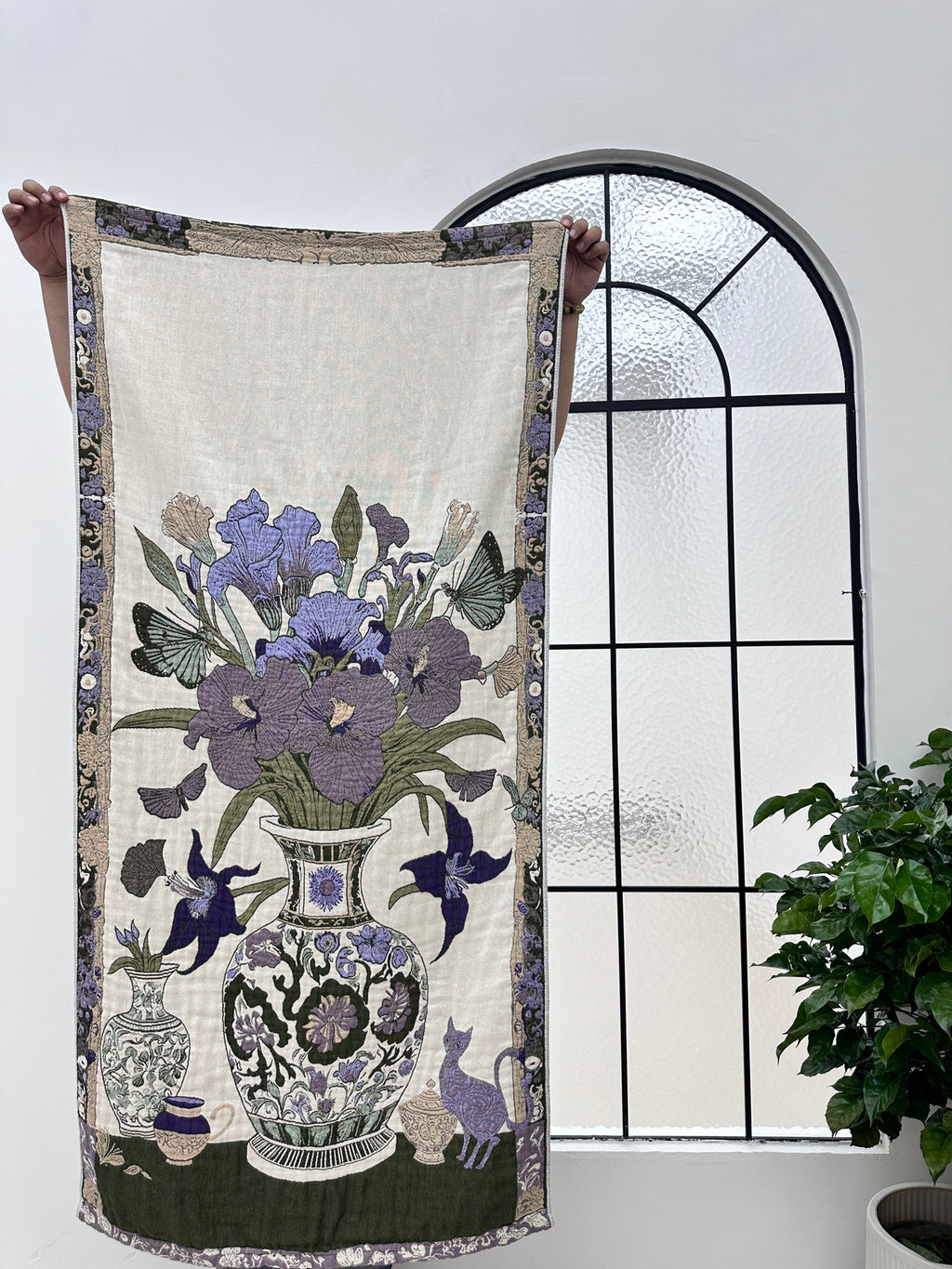 Full view of the Floribunda 29x59 cotton throw blanket held by an arched window