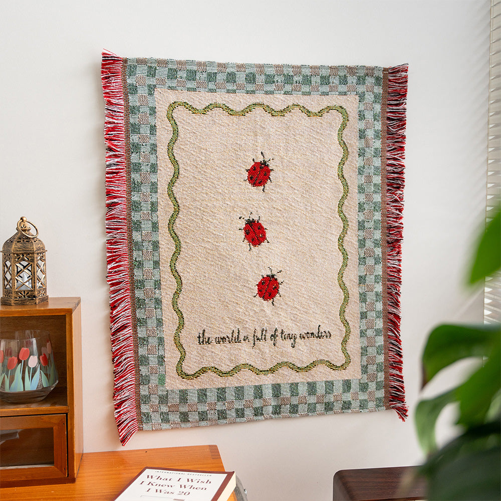Fablefolk Style F ladybug wall tapestry with sage checkerboard border and red side fringe